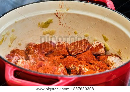 Preparing Perkelt Sauce - Pouring Dried Pepper On Meat In Red Pot