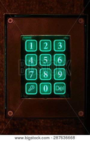 Doorphone of a building at night, illuminated number buttons glowing in the dark