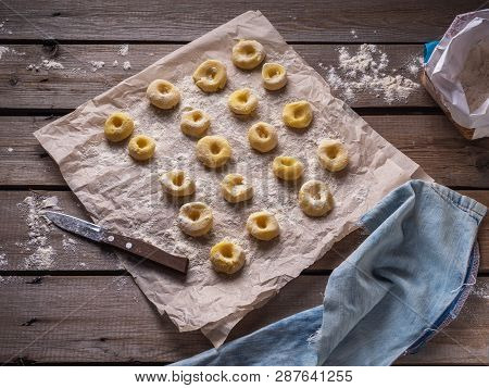 Potato Gnocchi, Laid Out On Parchment On A Plank Table, In The Foreground A Denim Cloth, In The Back