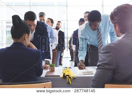 Front view of diverse business people checking in at conference registration table in office lobby