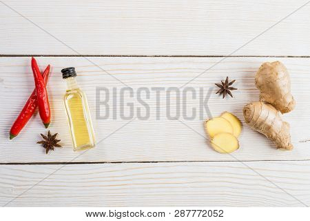 Layout Of  Ginger And  Ginger Oil Bottle And Condiments On Light Wooden Background.
