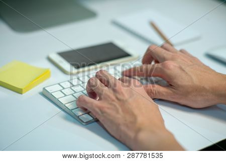 Closeup Selective Focus On Hands Of Businessman Typing On The Keyboard With Defocused Stationaries A