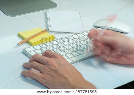 Selective Focus On White Keyboard Of Desk Top With Blurred Motion Of Hands Spinning The Pencil In Fo