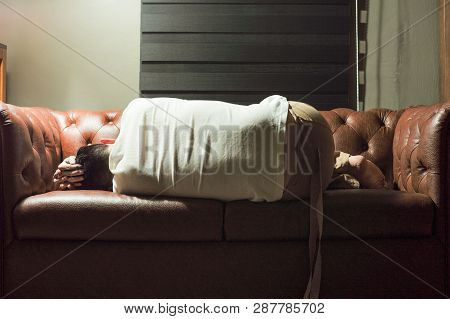 Portrait Of Sleeping Thoughtful Man On Vintage Sofa In The Living Room With Lighting Lamp