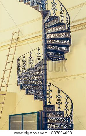 Vintage Wrought Spiral Stairs And Bamboo Ladder On Wall