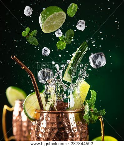 Famous splashing Moscow mule alcoholic cocktail in copper mugs, freeze motion effect.