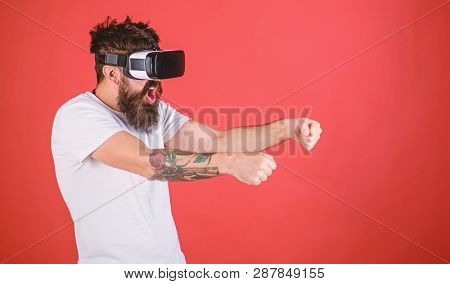 Virtual Racing Concept. Man With Beard In Vr Glasses Driving Car, Red Background. Guy Play Racing Ga