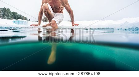 Young man with lean muscular body sits on the ice and going to swim in the cold winter water. Splitted image with underwater view of the ice hole