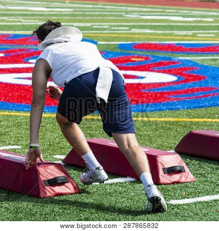 A High School Football Player Is Sprinting Between Barriers Suring A Pre-season Summer Camp Workout.