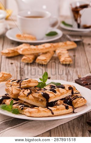Puff Pastry Cookies With Chocolate Icing On White Dish.