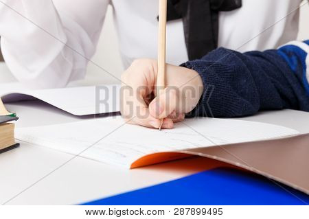 Mother And Her Son Doing Homework In The White Room. Whriting Homework In A Note.