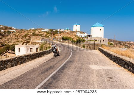 Sifnos, Greece - September 11, 2018: A Greek Man Riding A Motorbike Along The Way On The Island Of S
