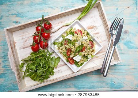 Pasta With Mozarella Cheese, Arugula And Vegetables On A Wood Background
