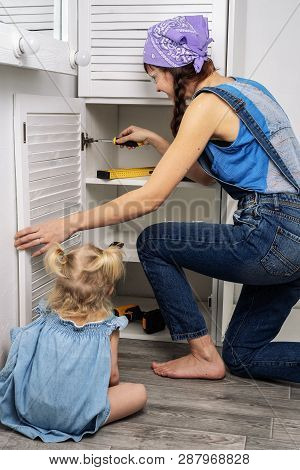 Mother Instead Of Father: Little Daughter Helps Mother To Repair Furniture.