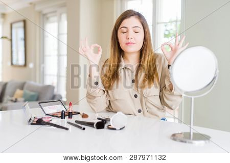 Beautiful young woman using make up cosmetics relax and smiling with eyes closed doing meditation gesture with fingers. Yoga concept.