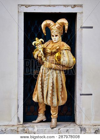Venice, Italy - March 1, 2019  A Person Dressed With A Gold Arlequin Costume During Venice Carnival 