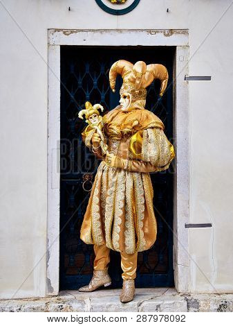 Venice, Italy - March 1, 2019  A Person Dressed With A Gold Arlequin Costume During Venice Carnival 