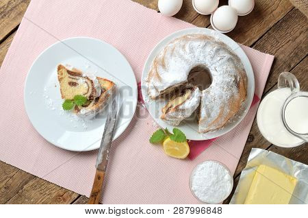 View From Above Of Sliced Of Bundt Cake Sprinkled With Sugar, Lemon, Melissa, Milk, Eggs And Butter