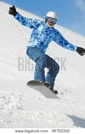 Snowboardåkare balanserar när flugor i hoppa på snowboard över snöiga skidbacken.