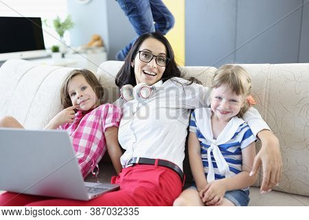 Smiling Woman Sitting With Laptop And Children On Couch. Business For Women At Home Concept
