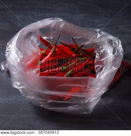 Hot Pepper In A Plastic Bag On A Black Surface. The Concept Is Plastic Free.
