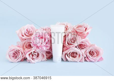 Mockup Of Unbranded White Bottle For Branding And Label And Light Pink Roses On A Pastel Blue Backgr