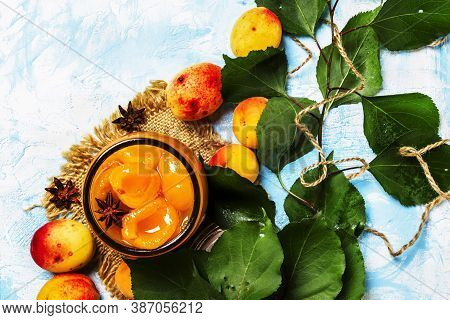 Apricot Jam In Glass Jar With Anise Stars And Fresh Apricots With Leaves, Top View