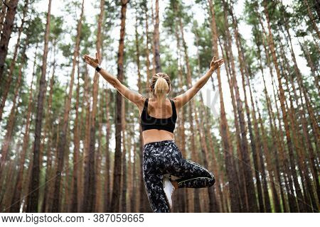 Beautiful Woman Standing And Doing Yoga In Forest. Exercise And Meditation Concept. Pay Obeisance Or