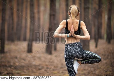 Beautiful Woman Standing And Doing Yoga In Forest. Exercise And Meditation Concept. Pay Obeisance Or