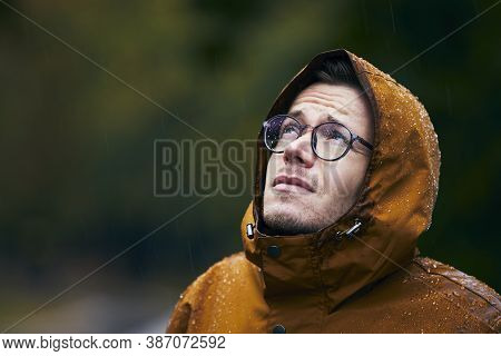 Heavy Rain During Autumn Day. Portrait Of Young Man In Waterproof Jacket.