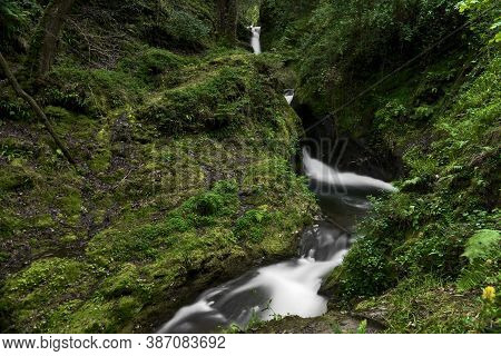 Beautiful Small Narrow Waterfall In Magic Forest. Tiny Waterfall. Long-exposure Photo Of Poulanass W