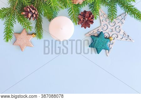 Upper Fir Border, Stars, White Candle And Pine Cones On A Pastel Blue Background. Top View Of Christ