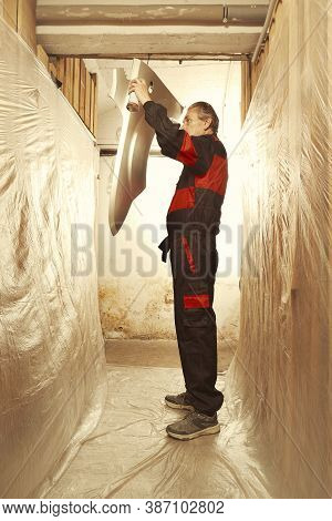 Man Spraying And Repairing In Basement Car Fender For Replacing