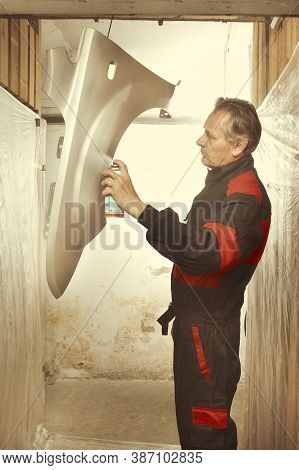 Man Spraying And Repairing In Basement Car Fender For Replacing