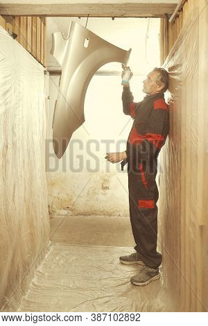 Man Spraying And Repairing In Basement Car Fender For Replacing