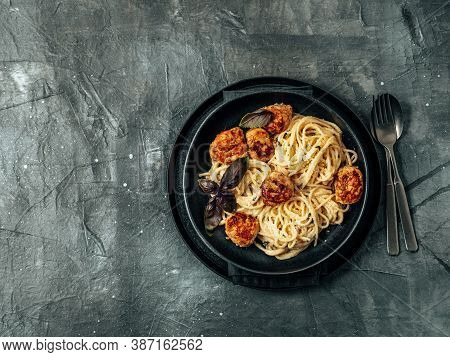 Zucchini Parmesan Meatballs With Pasta Carbonara In Black Craft Plate Over Gray Background. Close Up