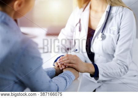 Unknown Woman-doctor Is Holding Her Patients Hands, Discussing Current Health Examination, While The