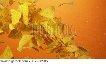 Flying tortila chips up in the air in freeze motion. Isolated on orange background