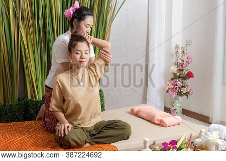 Thai Masseuse Doing Massage For Woman In Spa Salon. Asian Beautiful Woman Getting Thai Herbal Massag