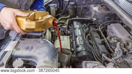 Mechanic Topping Up The Oil In A Car Pouring A Pint Of Oil Through A Funnel Into The Engine, Close U