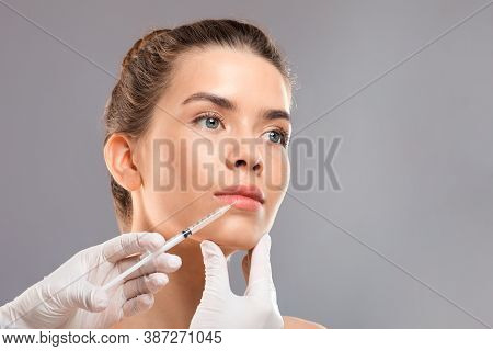Aesthetic Modern Cosmetology Concept. Lip Injection For Young Woman Over Grey Studio Background, Clo