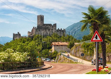 Drena, Italy - 07 19 2017: Castello Di Drena, Near Lake Lago Di Garda - Castle On Hill. Road, Palm T