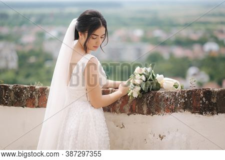 Beautiful Bride Stand In Frind Of City View With Bouquet And Smile