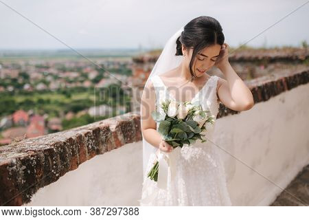 Beautiful Bride Stand In Frind Of City View With Bouquet And Smile