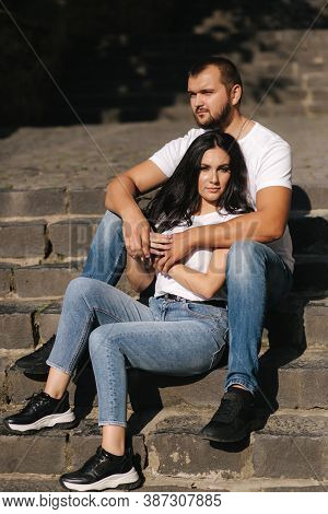 Man And Woman Sit On The Stairs In The Ciry. Sun Shine