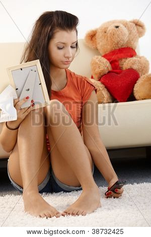 Lovelorn 십 대 소녀, 가정에서 바닥에 앉아 슬픈 찾고.
