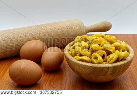 Raw Tortellini In A Wooden Bowl With Rolling Pin And Eggs. Traditional Italian Cuisine.