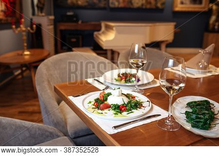 Restaurant Table Served With Spanish Buratta Tomato And Peppers Salads