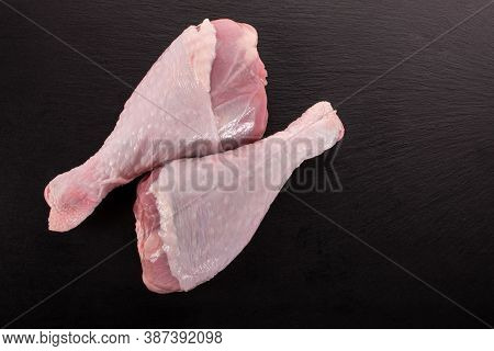 Two Raw Turkey Legs On Black Slate Background. Closeup Two Raw Turkey Legs On Dark Stone Board