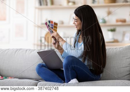 Online Design Courses. Young Brunette Asian Woman Holding Colour Swatch And Using Laptop At Home, St